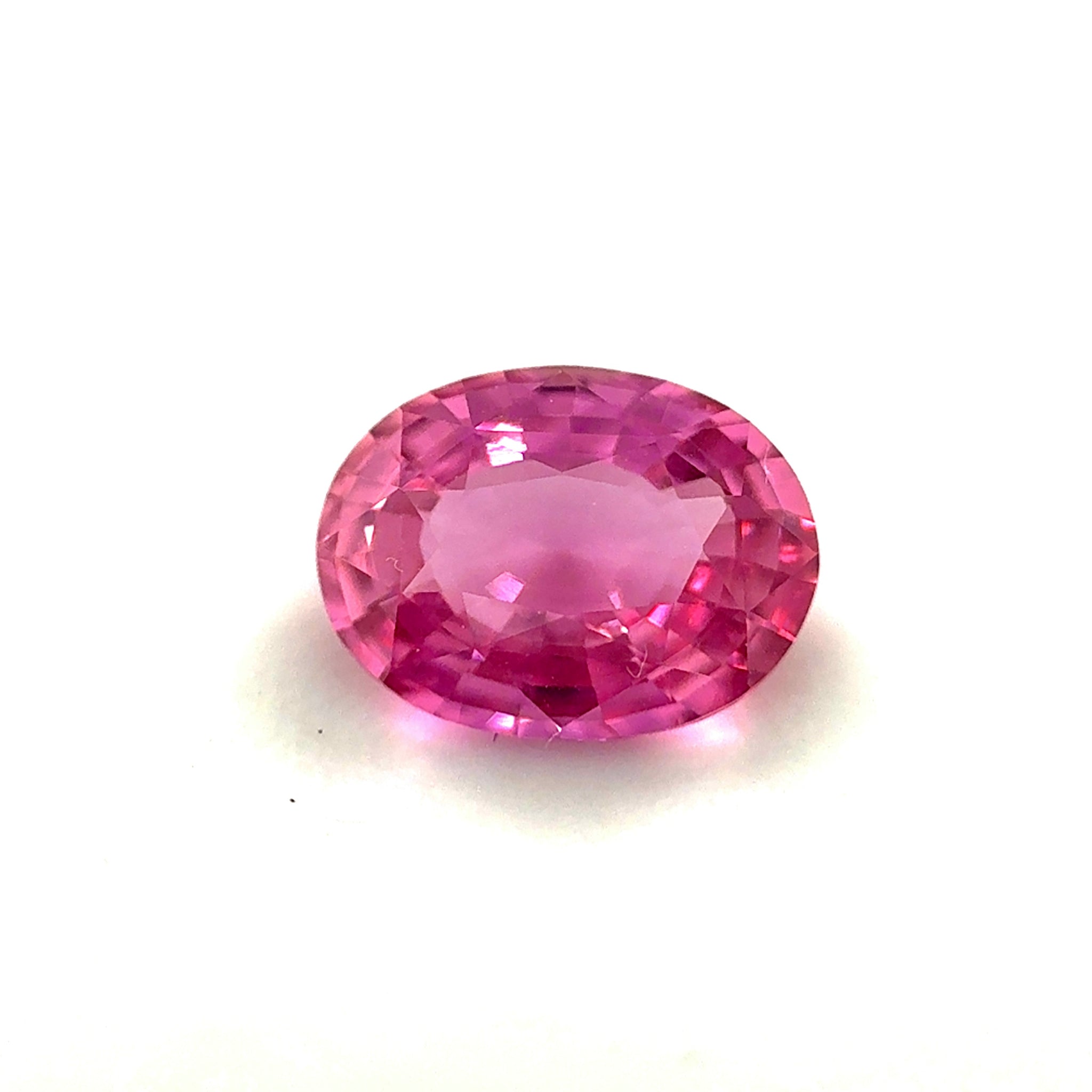 Oval cut Padparadscha sapphire showing brilliant luster and faceting under daylight