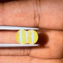 Collector’s twin Chrysoberyl Cat’s Eye gemstone photographed in daylight on fingertips for scale.