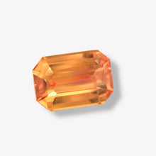 Emerald cut Padparadscha sapphire showing brilliant luster and faceting under daylight
